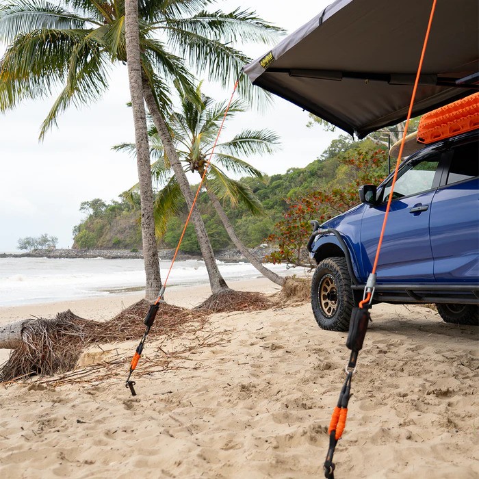 01 Tiegear Beach Awning A truck is parked on a beach with its awning deployed.