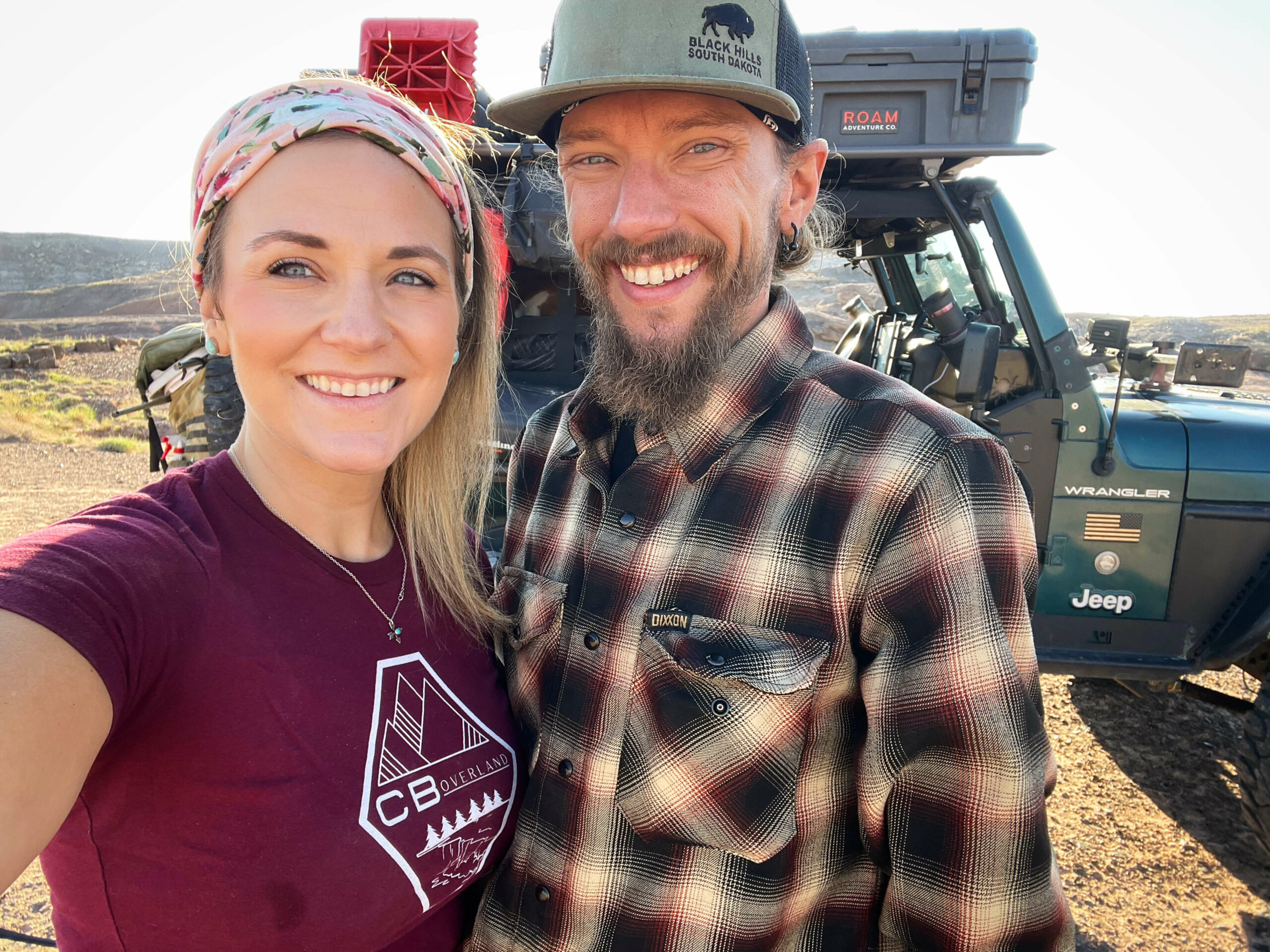 3F34C4BB-86E9-4647-8E84-909BA443DC6B Chelsea and Blake stand in front of their overlanding jeep.