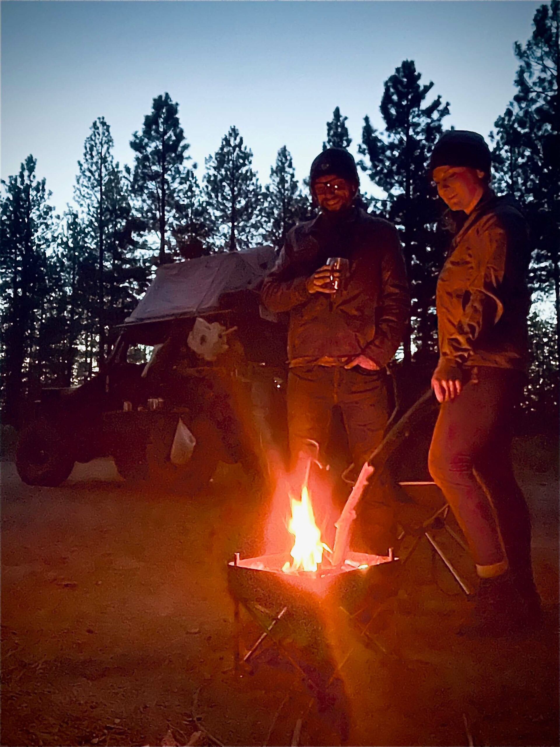 C47CB1CD-30A7-4C7F-8DBD-4508DAC323CB Blake and Chelsea stand in front of a campfire during an overlanding adventure.