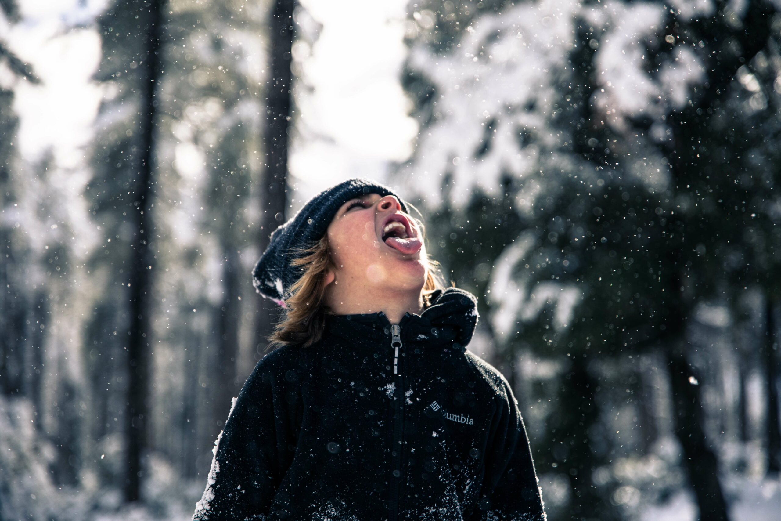 patrick-fore--kpz7pVyQY4-unsplash Young boy catching snowflakes on his tongue in the forest